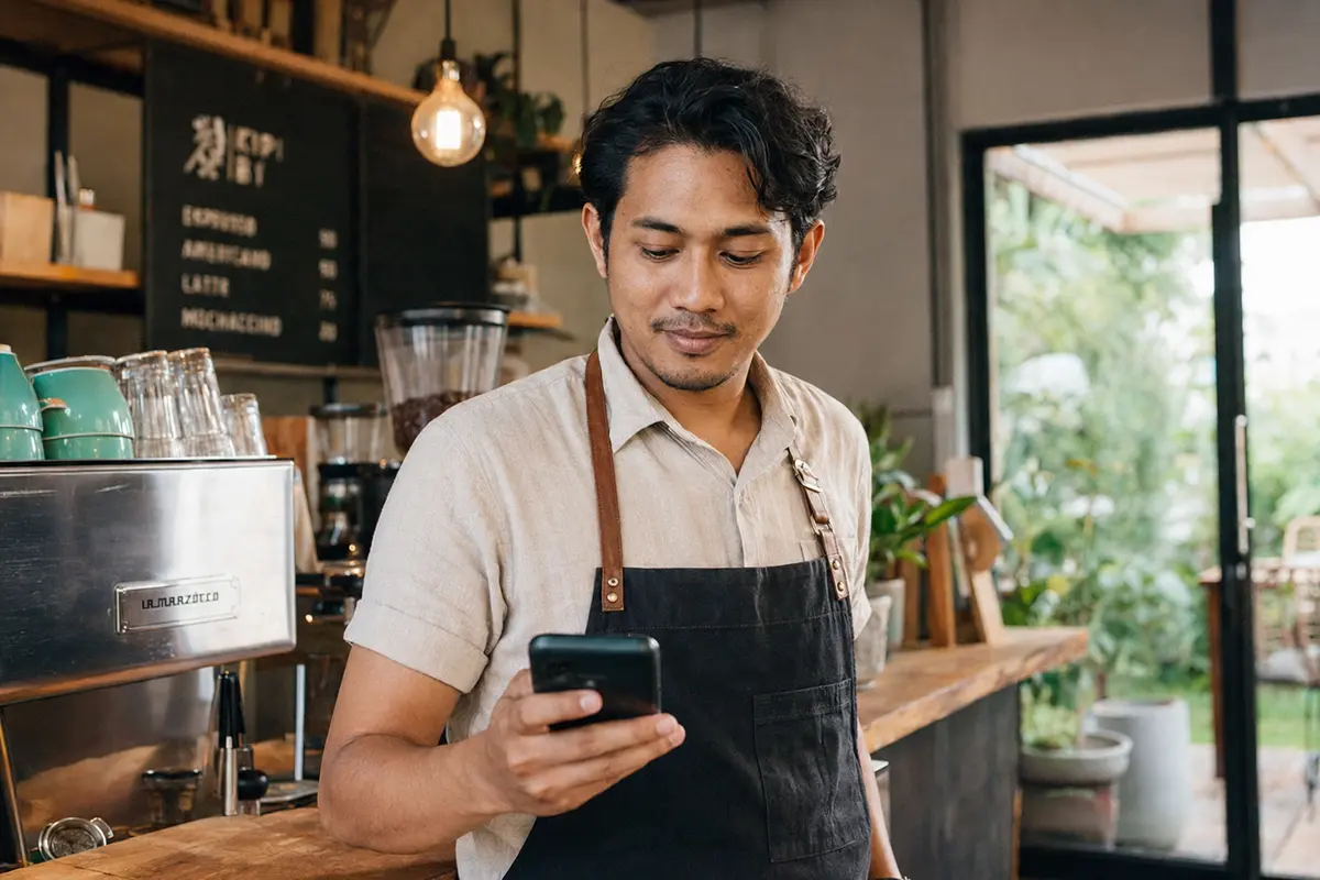 Pemilik kafe memeriksa kehadiran karyawan di HP-nya